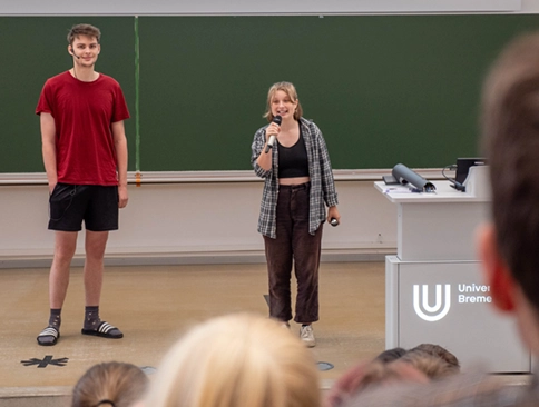 Zwei Studierende präsentieren vor Publikum im Hörsaal der Universität Bremen.